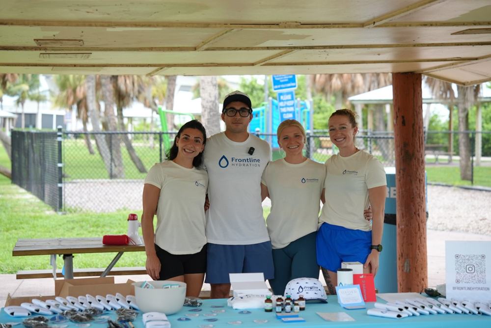 The Frontline Hydration team smiling behind their branded event table