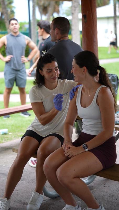 Provider giving a smiling client a wellness shot outdoors