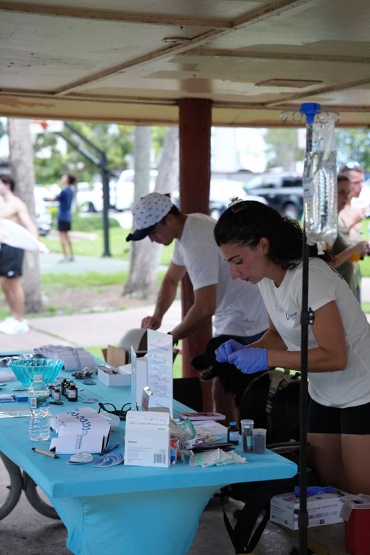 Team member preparing shots at an outdoor event table