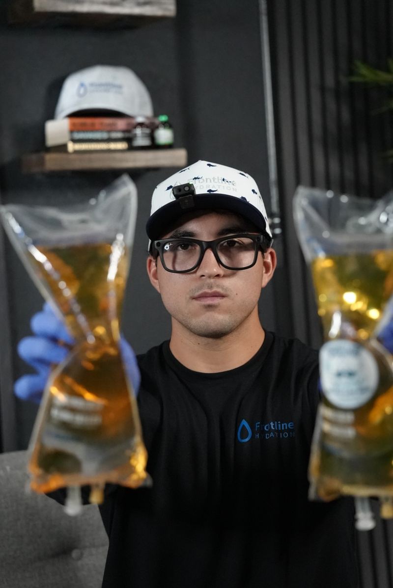 Gabe holding two vitamin IV bags in the Frontline lounge