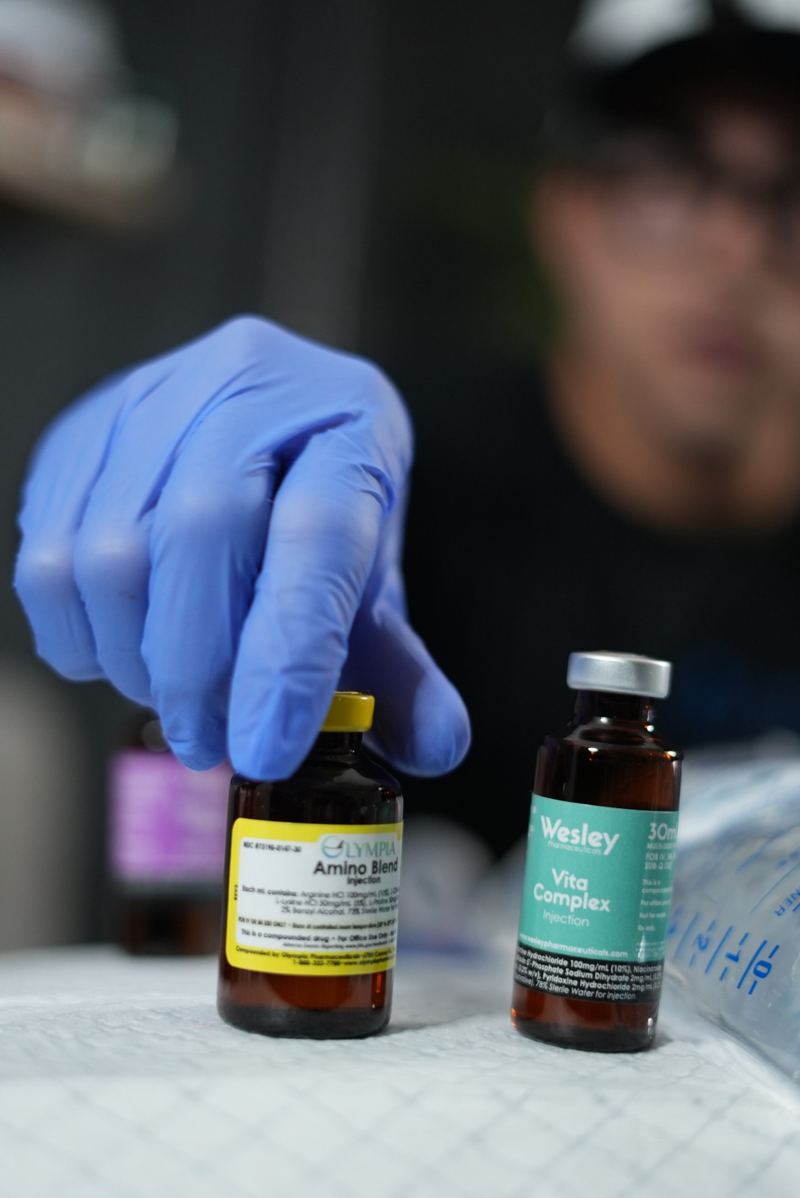 Gloved hand selecting vitamin vials before a visit